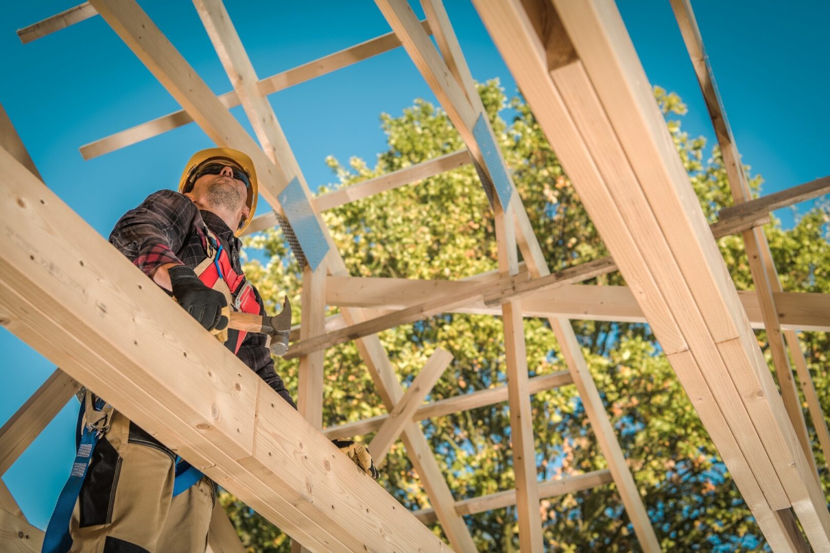 Wooden roof construction showing exposed timber trusses, rafters, and structural framing during roof installation.